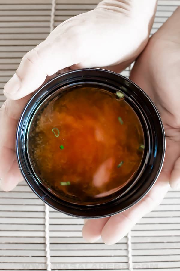 hands holding misoshiru soup in a bowl