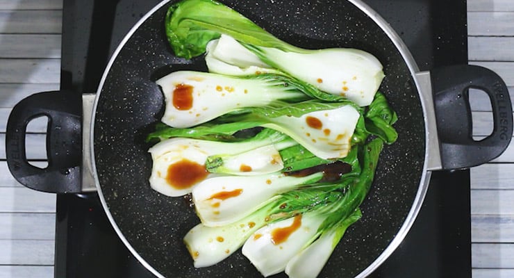 bok choy leaves in a pan with stir fry sauce