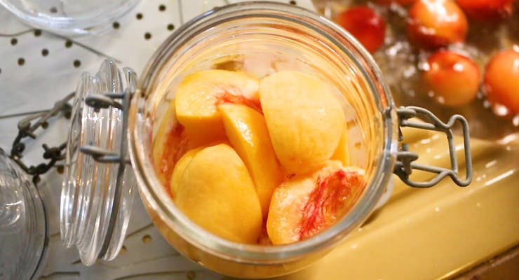 place cut peach into jars