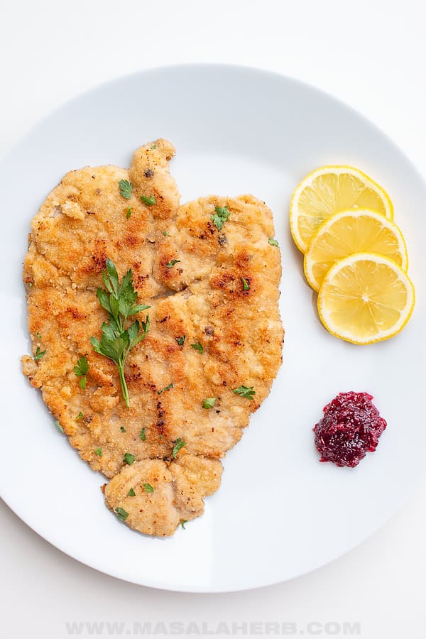 Wiener Schnitzel with veal meat, lemon slices, parsley and lingonberry jam