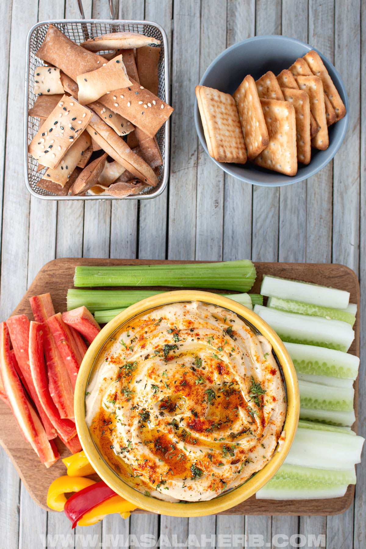 Hummus without Tahini in a serving bowl top view down with vegetable dippers and lavash chips and crackers