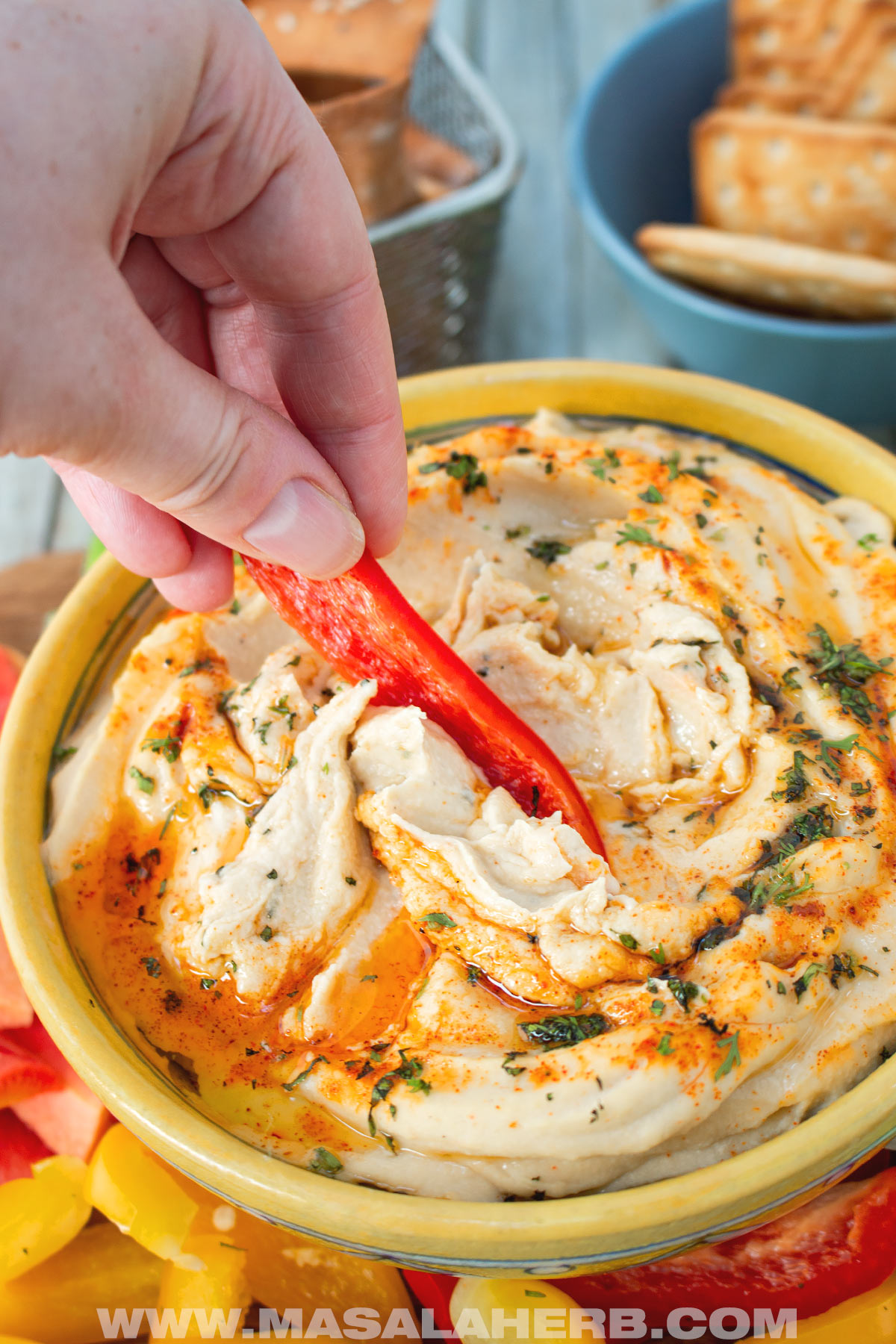 dipping with red bell pepper strip in hummus