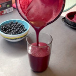 pouring blueberry smoothie into glass