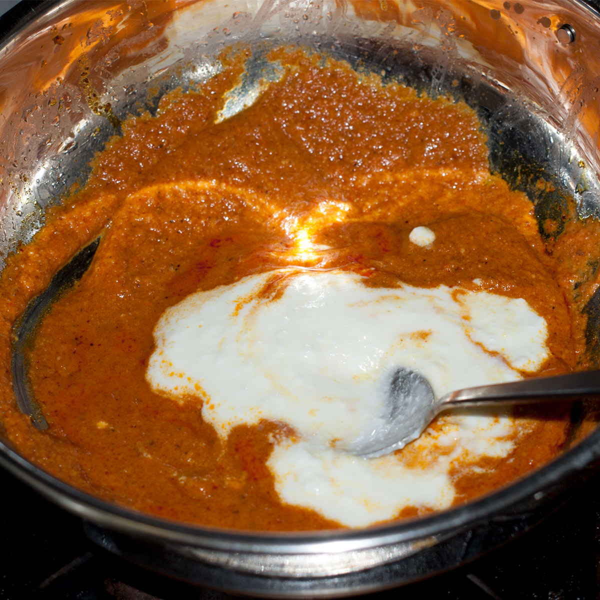 stirring in yogurt and cream to make paneer korma curry