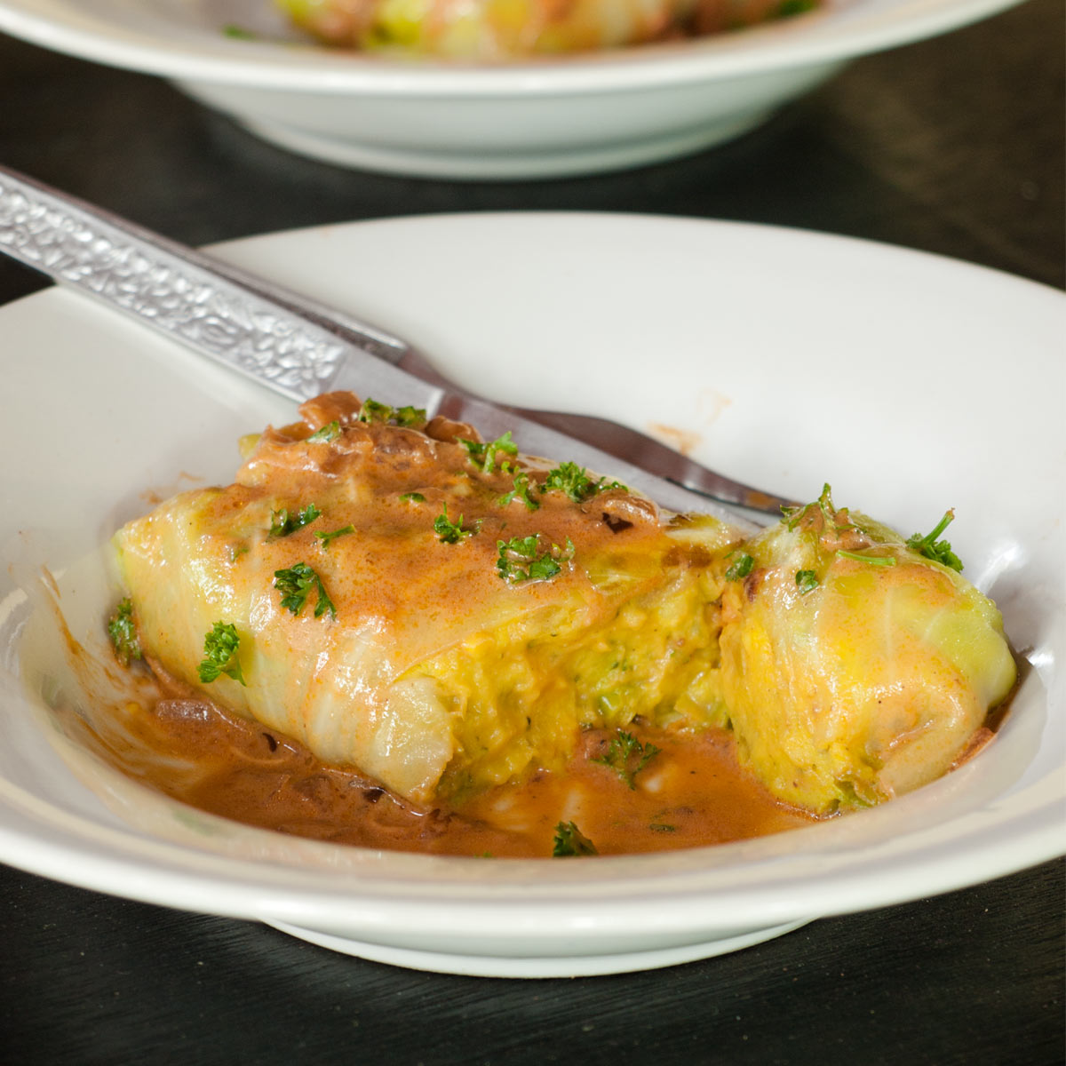 Vegetarian Stuffed Cabbage Roll in a plate with a tomato cream sauce