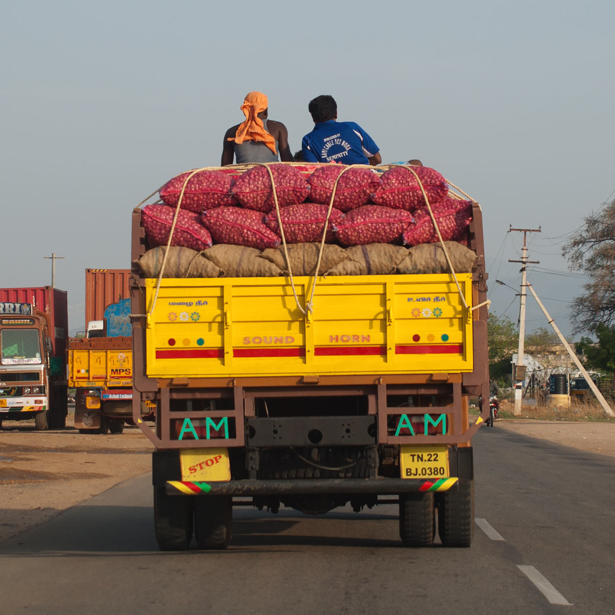 two guys sitting on a truck loaded with onions