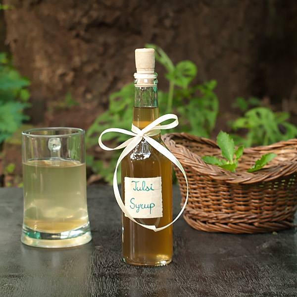 Tulsi Syrup bottle with fresh tulsi and holy basil syrup mixed with water.