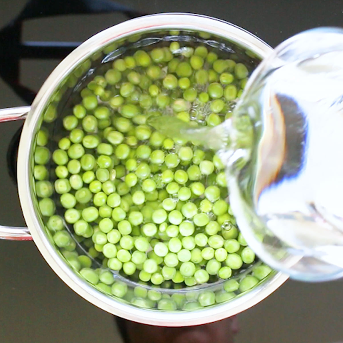 pour water over green peas in sauce pan