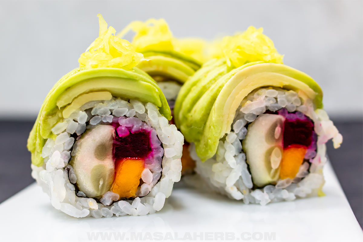 Avocado topped inside out sushi filled with cucumber beet and mango