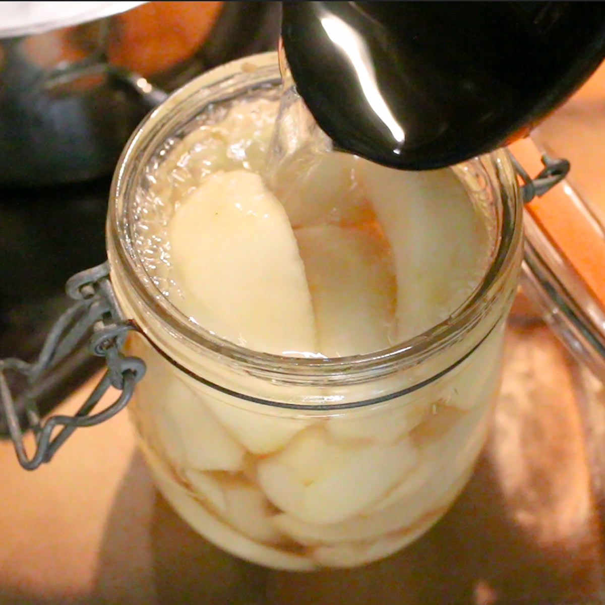 pour homemade syrup over pears in the jar