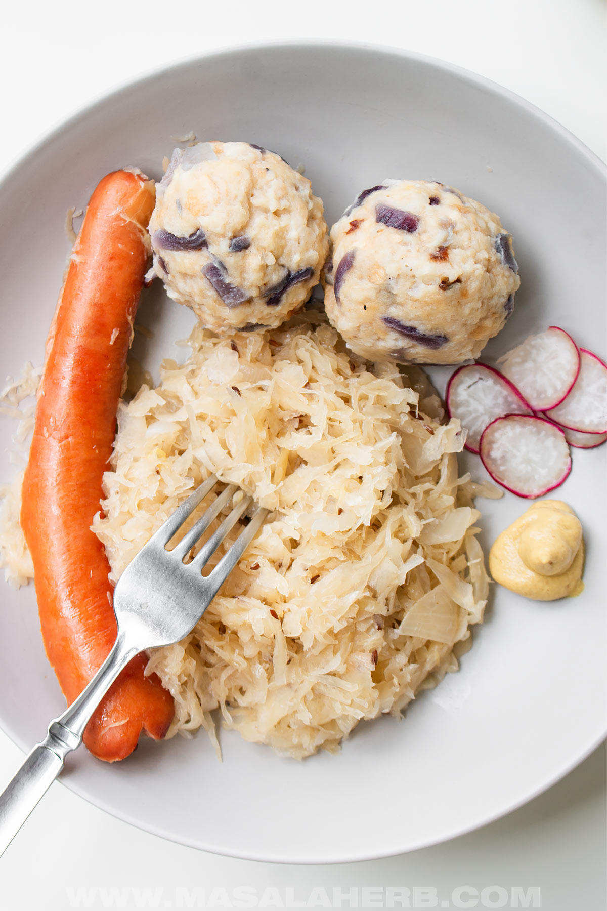 Plate of homemade Sauerkraut and sausage, dumplings, radish and German mustard.