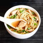 A bowl of Chinese noodle soup and chicken