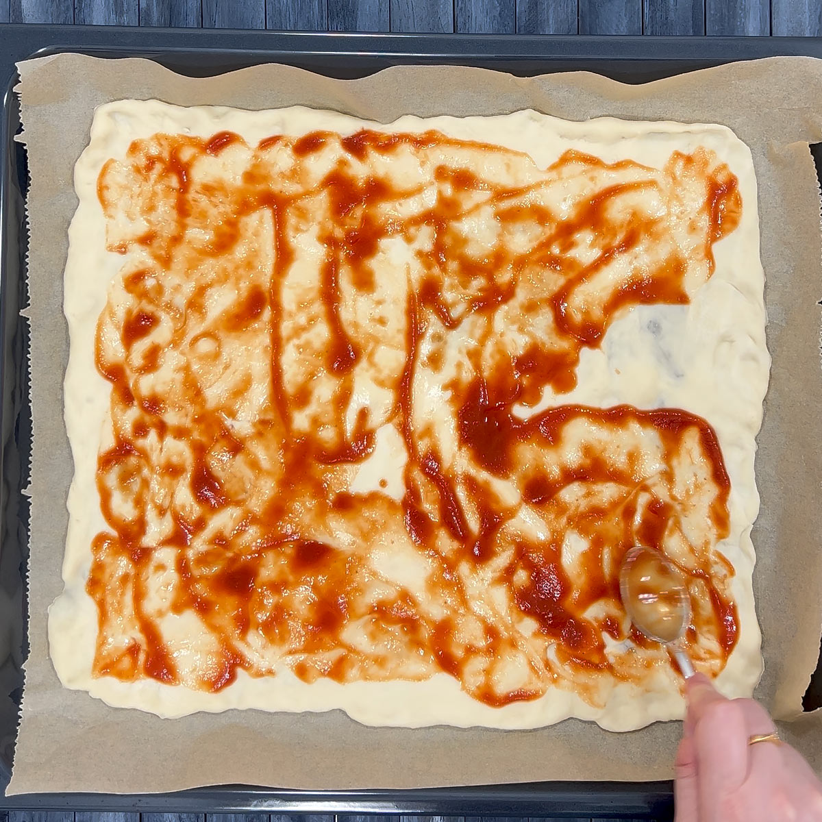 top pizza dough with tomato sauce