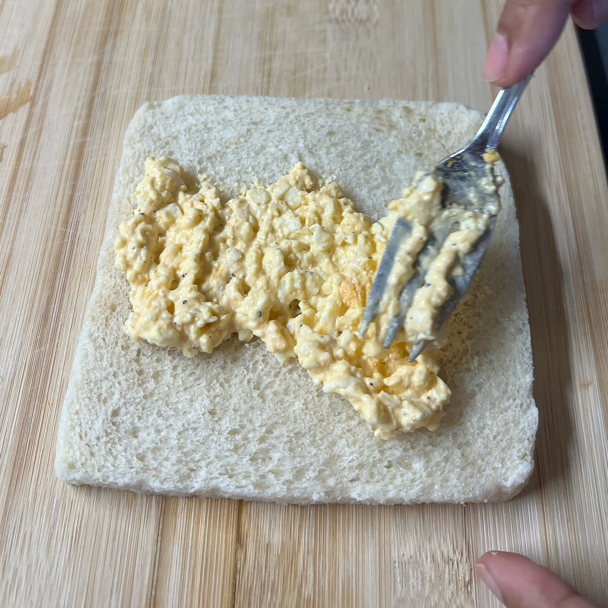 spread egg salad over slice of bread