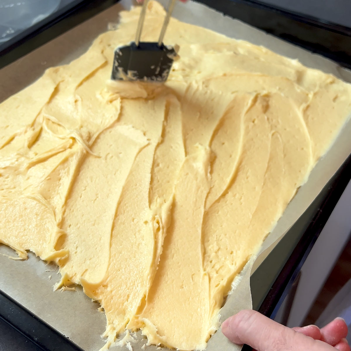 spread cake batter over a parchment lined tray