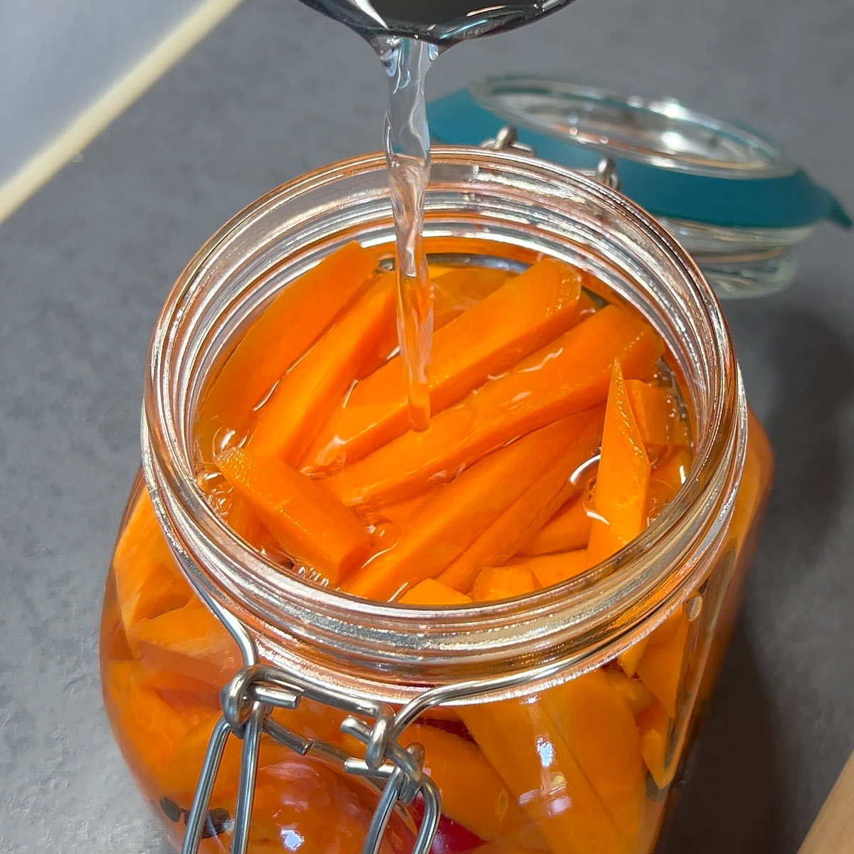 pour vinegar and water over the carrots in the jar
